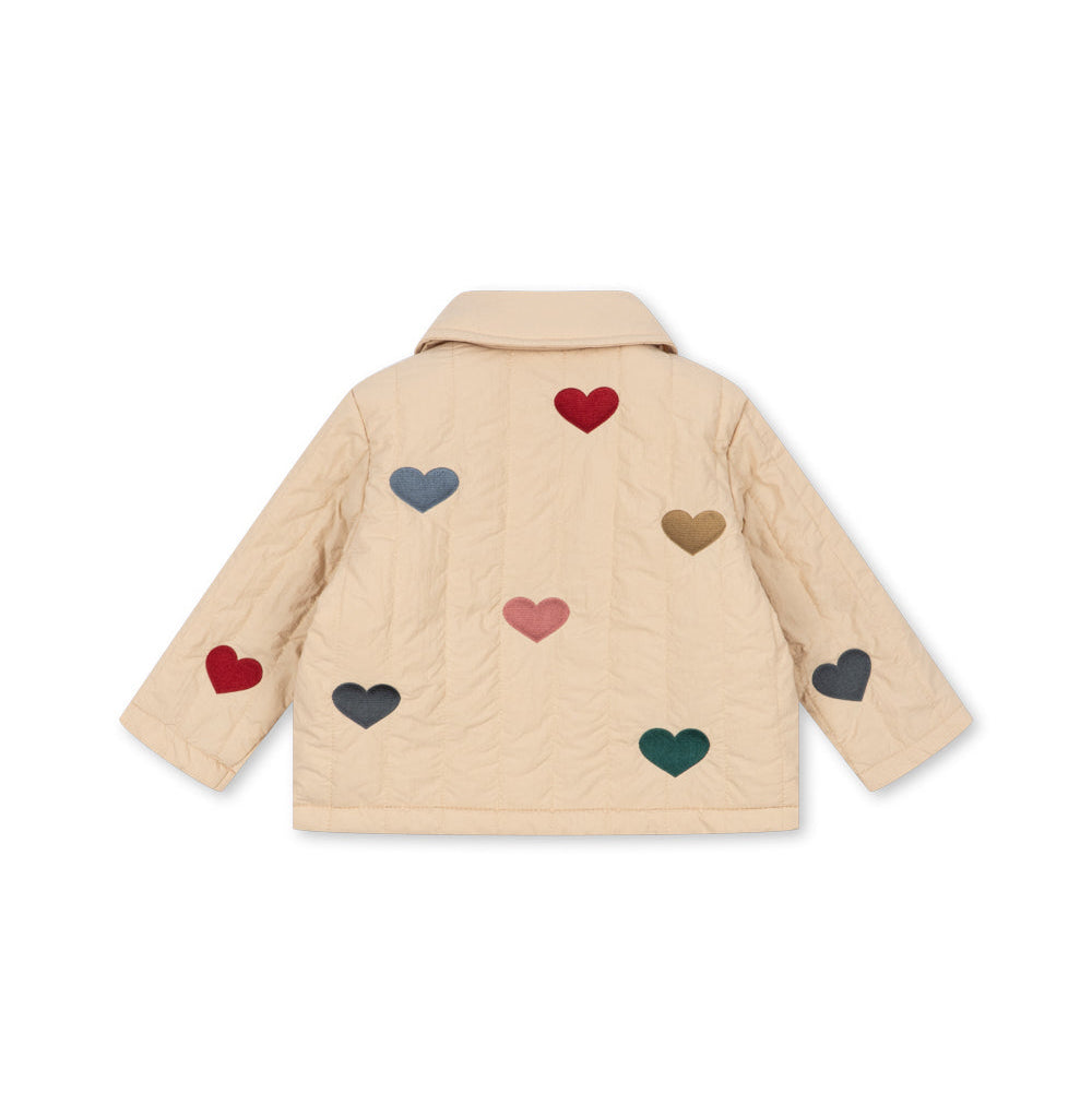 A beige quilted jacket with multiple colorful heart patches in red, blue, pink, brown, green, and gray, displayed against a solid white background.