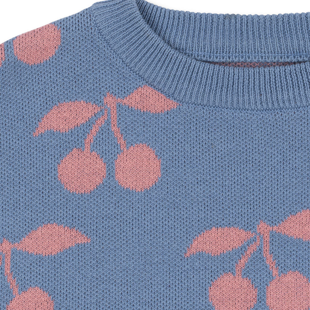 Close-up of a blue knitted sweater with pink cherry patterns
