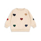 Beige sweater with colorful heart patterns on a white background