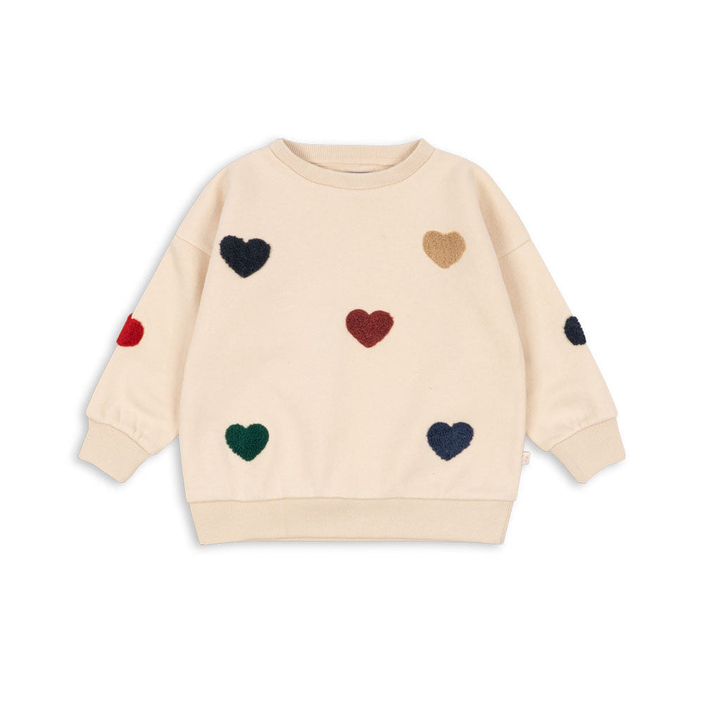 Beige sweater with colorful heart patterns on a white background