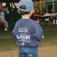 Child wearing a blue sweatshirt with text and cap, standing in an indoor equestrian arena.