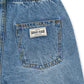 Close-up of blue denim shorts with a brand label on the pocket against a white background
