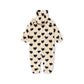 A cream-colored plush hooded baby jumpsuit covered in a black heart pattern, shown flat against a white background.