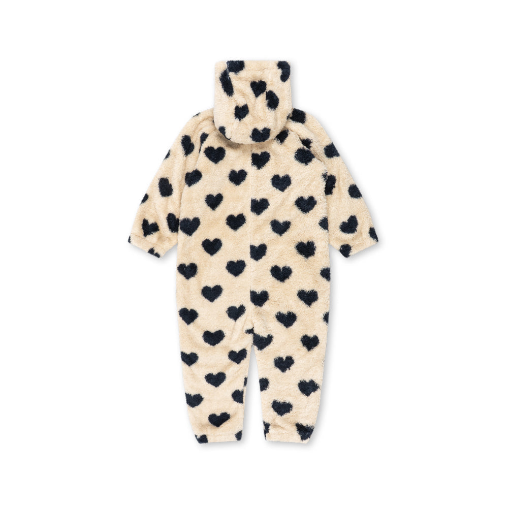 A cream-colored plush hooded baby jumpsuit covered in a black heart pattern, shown flat against a white background.