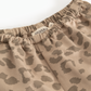 Close-up of a pair of Marmot pants featuring a beige and brown leopard print pattern and an elastic waistband.