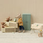 Miniature scene with a mouse character, teddy bears, and furniture in a room with beige walls and carpet.