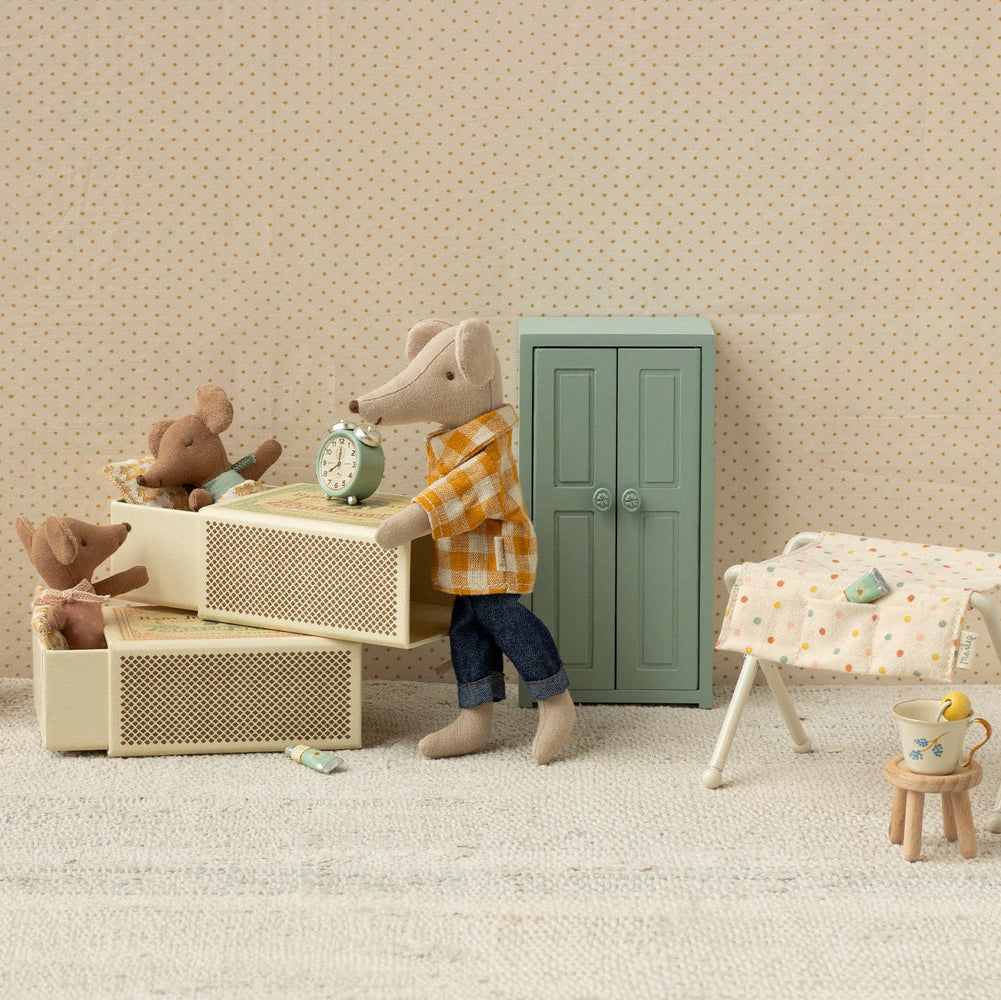 Miniature scene with a mouse character, teddy bears, and furniture in a room with beige walls and carpet.