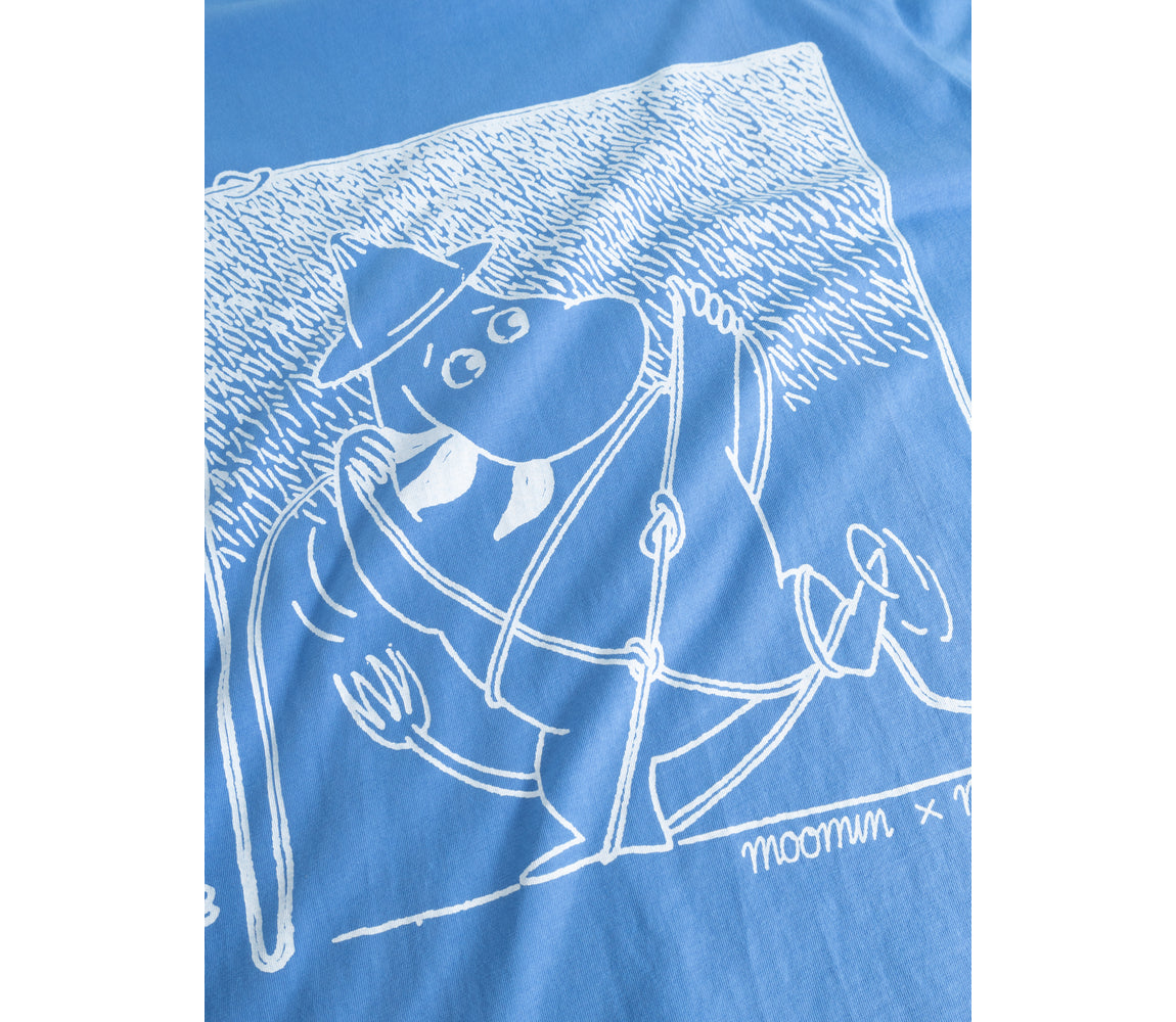 A close-up of a blue T-shirt featuring a white line-art graphic of Moomin characters, including Moomin and the text 'moomin x' near the lower right of the print.