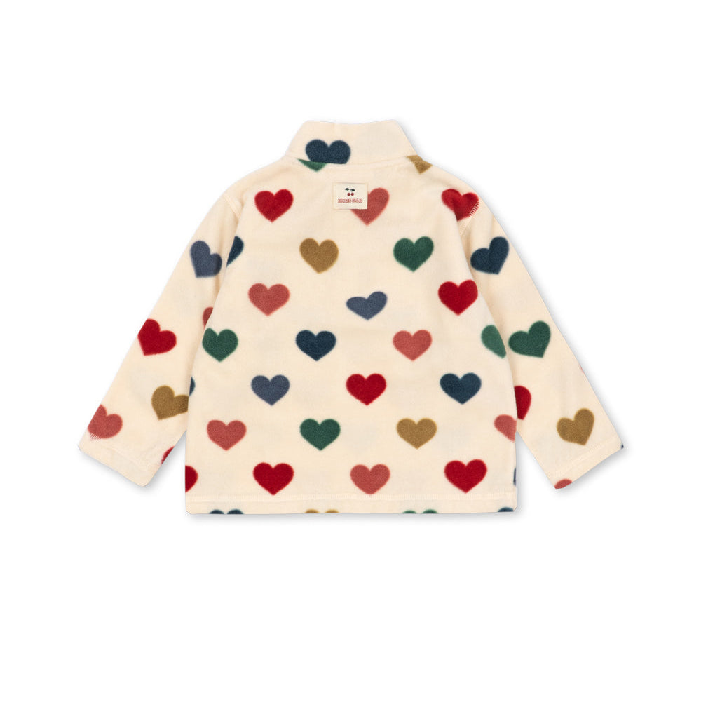 A cream-colored fleece jacket with a high collar, featuring an all-over pattern of small hearts in red, green, navy blue, and brown, displayed on a clean white background.