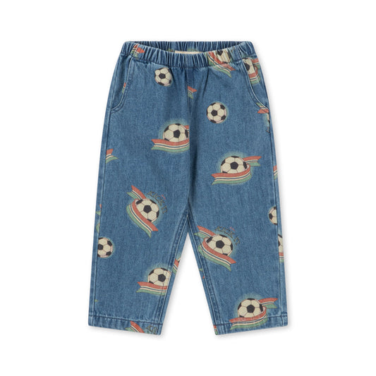 Blue denim pants for kids featuring an all-over print of soccer balls in space with colorful rockets and stripes, displayed flat against a white background.