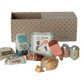 Set of toy food items and packaging in front of a cardboard box with a pattern.