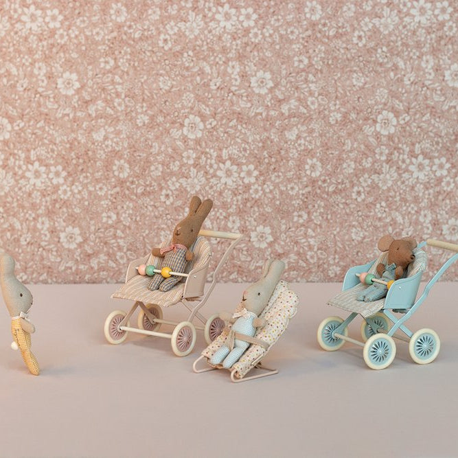 Toy bunnies in strollers with a floral wallpaper background