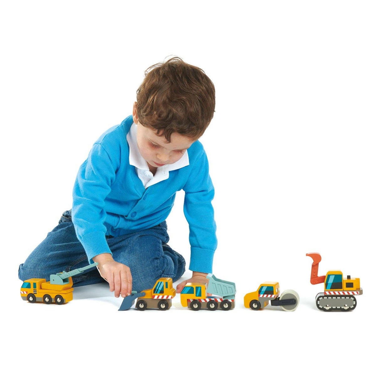 Child playing with toy construction vehicles on a white background