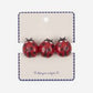 Three red ladybug earrings on a branded card against a white background