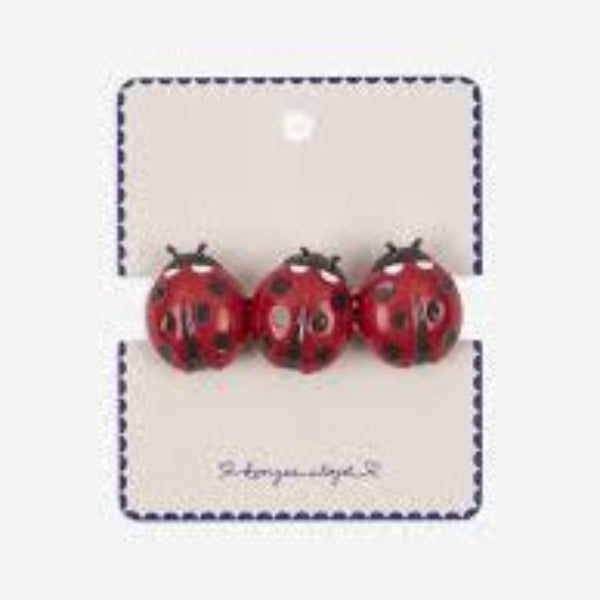 Three red ladybug earrings on a branded card against a white background
