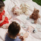 Two children playing with toys on a blanket outdoors.