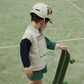 Child wearing a helmet and holding a skateboard on a green court
