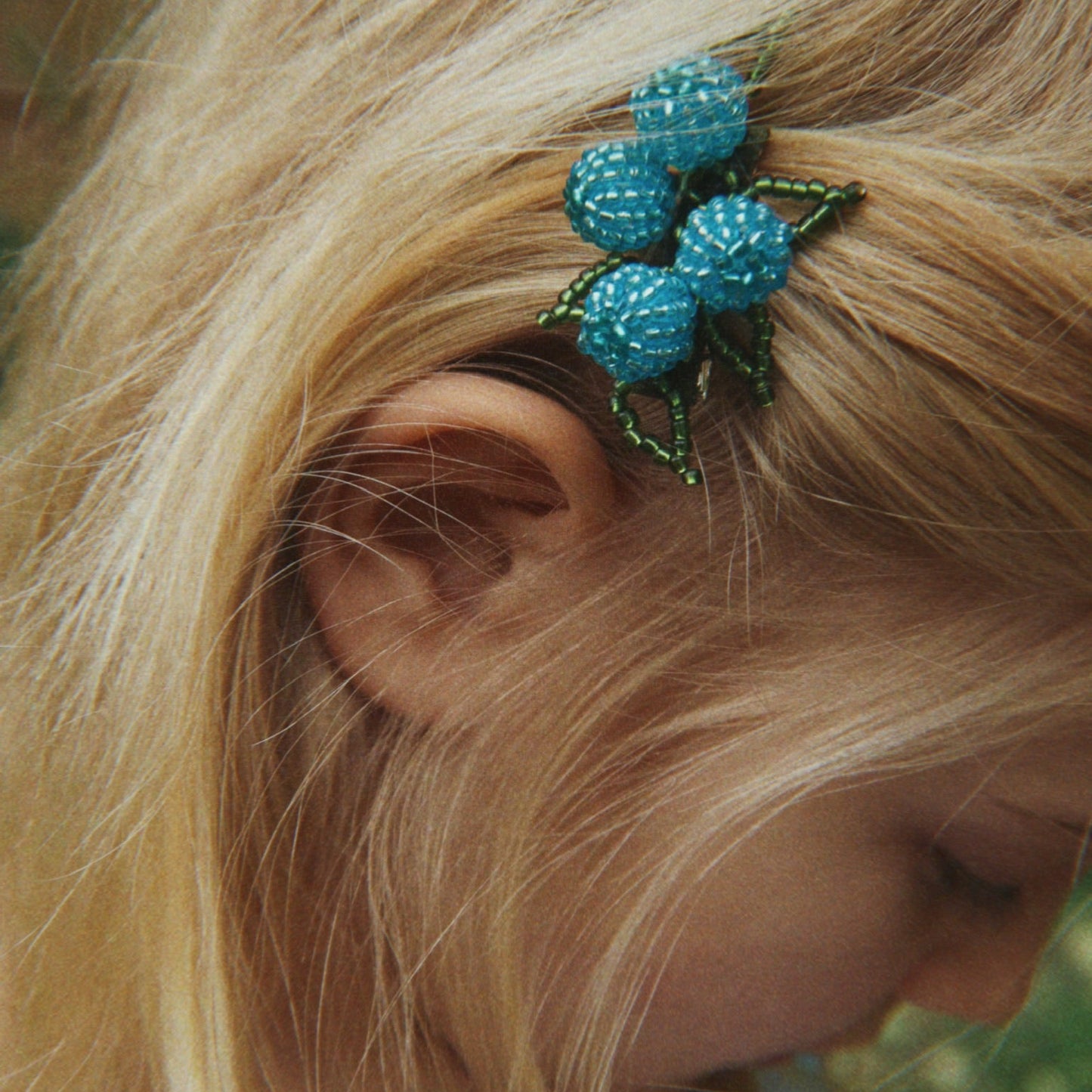 Close-up of a blue hair accessory worn by a person with blonde hair.