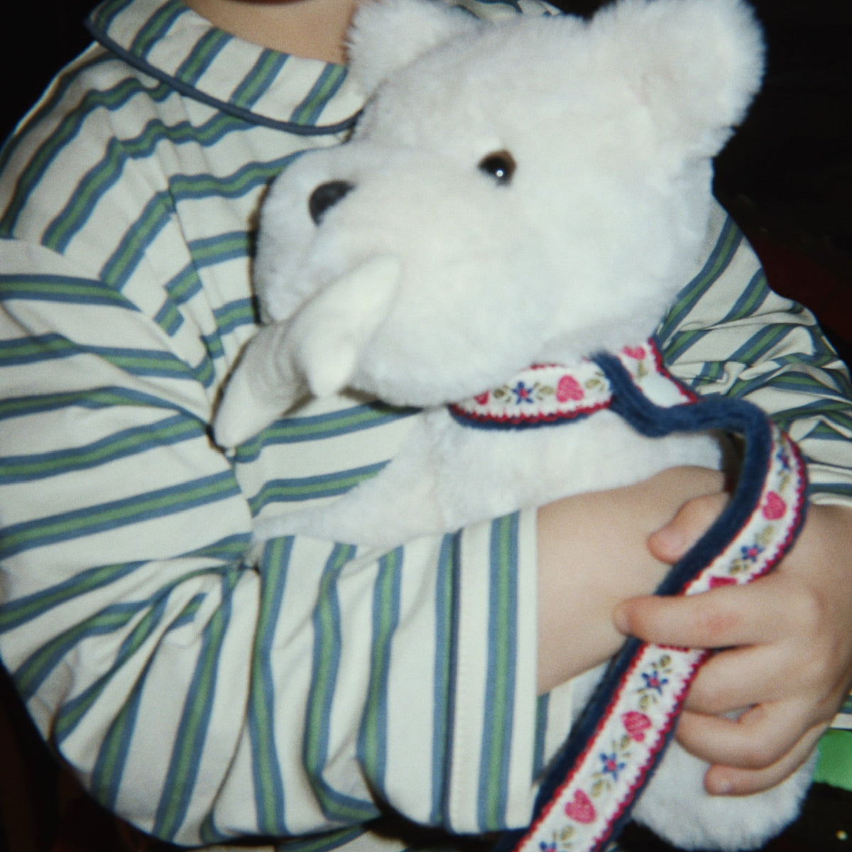 Child holding a white teddy bear with a dark background