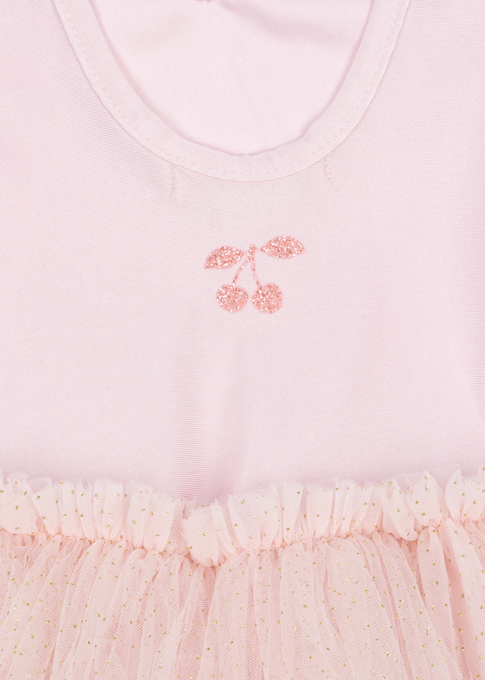 Close-up of a light pink children's dress with a glittery pink cherry motif on the chest and a ruffled tulle skirt with tiny gold speckles.