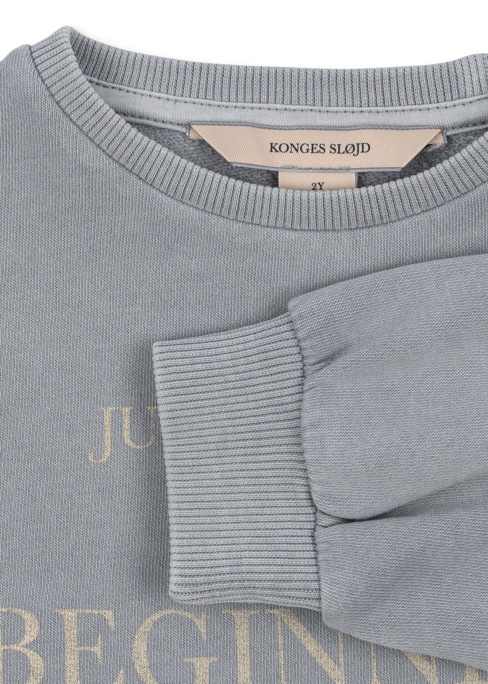 Gray sweater with 'Konges Slojd' label and text on fabric