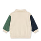 Beige sweater with green and navy sleeves on a white background