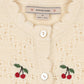 Close-up of a cream-colored knit cardigan featuring scalloped edges, white buttons, and embroidered red cherries with green leaves on both sides. The brand label reads 'KONGJES SLAJID'.