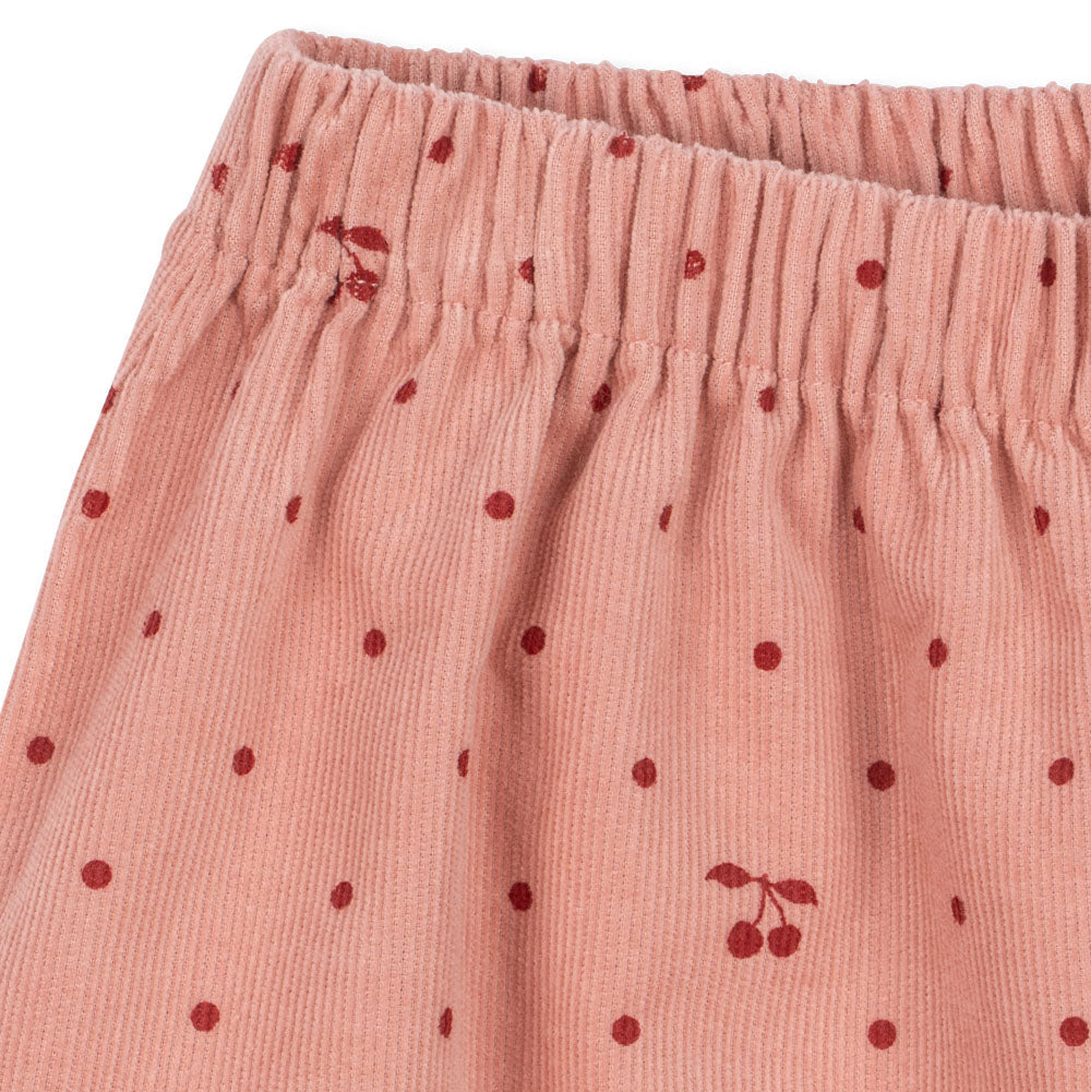 Close-up of pink pants with red cherry pattern on a white background