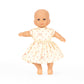 Baby doll wearing a white dress with red polka dots on a white background
