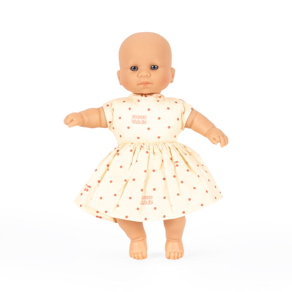 Baby doll wearing a white dress with red polka dots on a white background