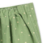 Close-up of a green fabric garment with a white polka dot pattern and an elastic waistband, shown against a plain white background.