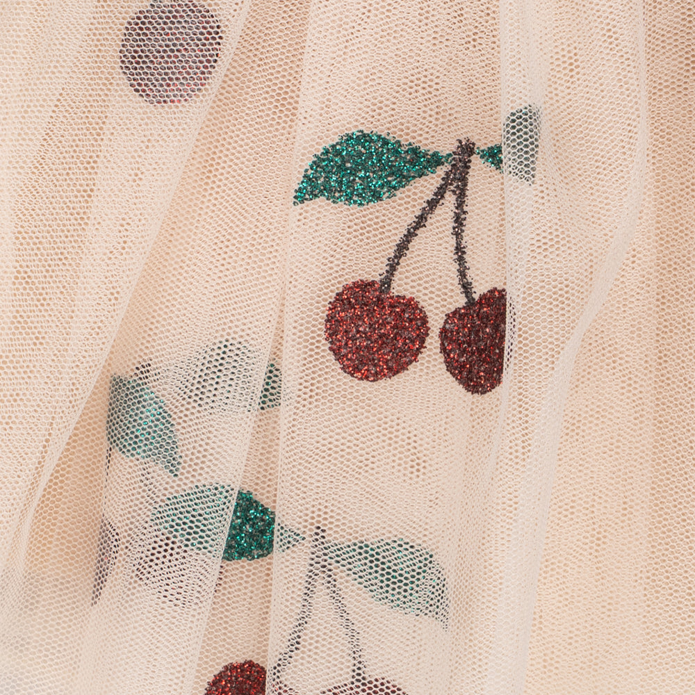 Close-up of a sheer cream tulle fabric with embroidered cherry motifs in red, green, and gray.