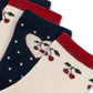 Three pairs of ankle socks arranged diagonally, featuring cherry and heart knit patterns. The socks come in cream, navy blue, and red, with the cream pair in the foreground showing a cherry motif and red cuff, the navy pair in the middle with a heart and white stars, and the top pair partially visible in red and navy.