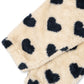 Close-up of a plush fleece blanket or throw in a warm cream color with dark navy heart-shaped spots, shown on a plain white background.