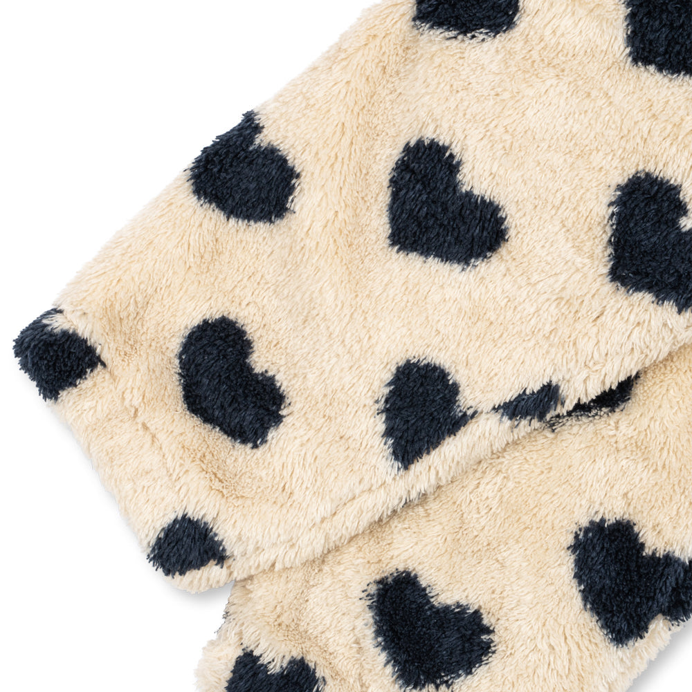 Close-up of a plush fleece blanket or throw in a warm cream color with dark navy heart-shaped spots, shown on a plain white background.