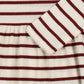 Close-up of a ribbed knit garment with horizontal burgundy and cream stripes, showing a folded cuff with a scalloped edge.