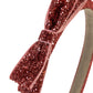 A close-up of a glittery red headband with a matching bow, shown against a plain white background.