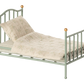 A miniature dollhouse-style metal bed frame in a pale sage green color, styled with a matching quilted cream quilt and pillow featuring a delicate floral pattern, set against a plain white background.
